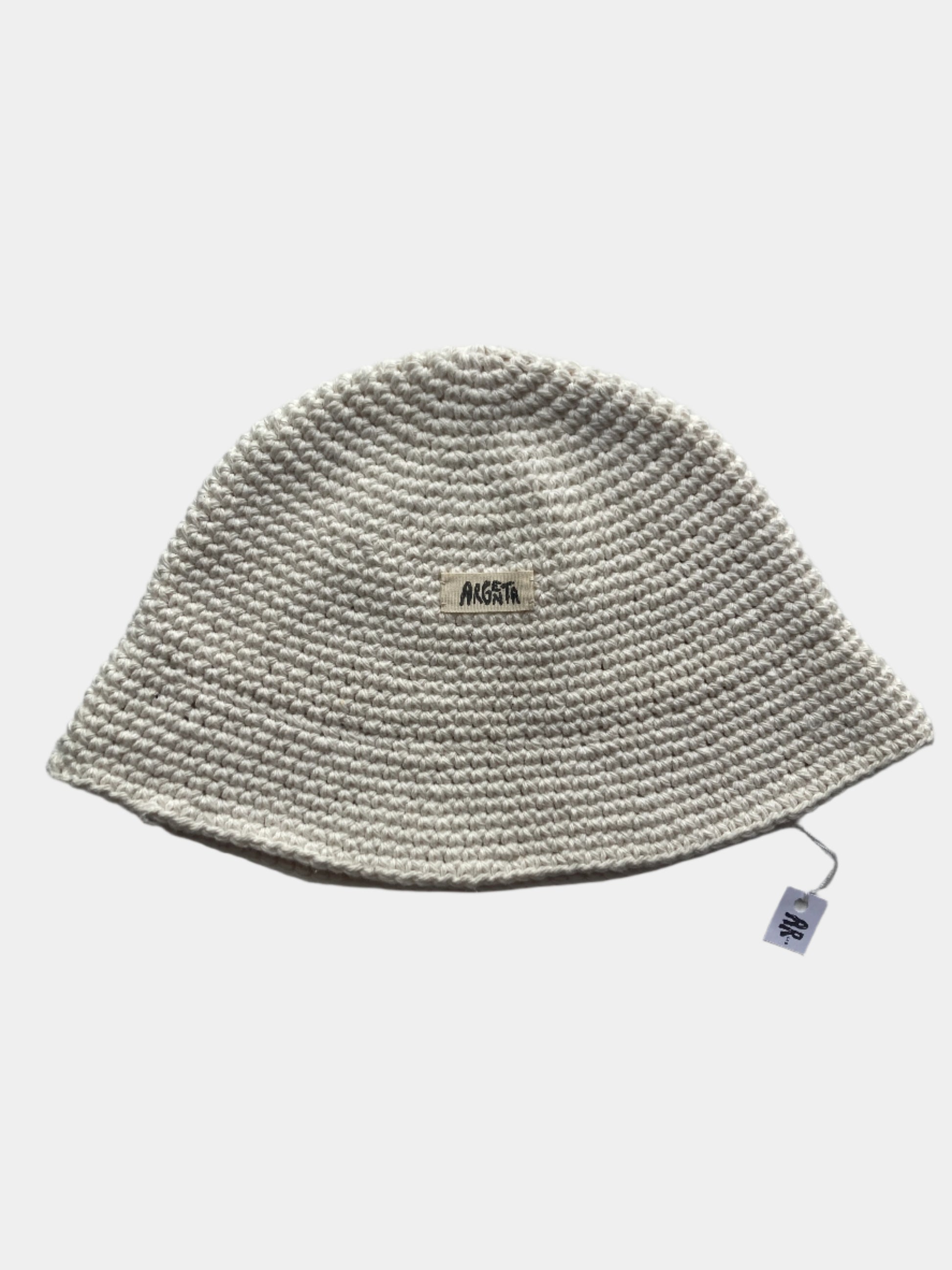 Knitted white beanie on a gray background with a brand label.