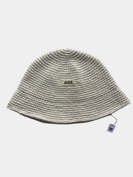 Knitted white beanie on a gray background with a brand label.